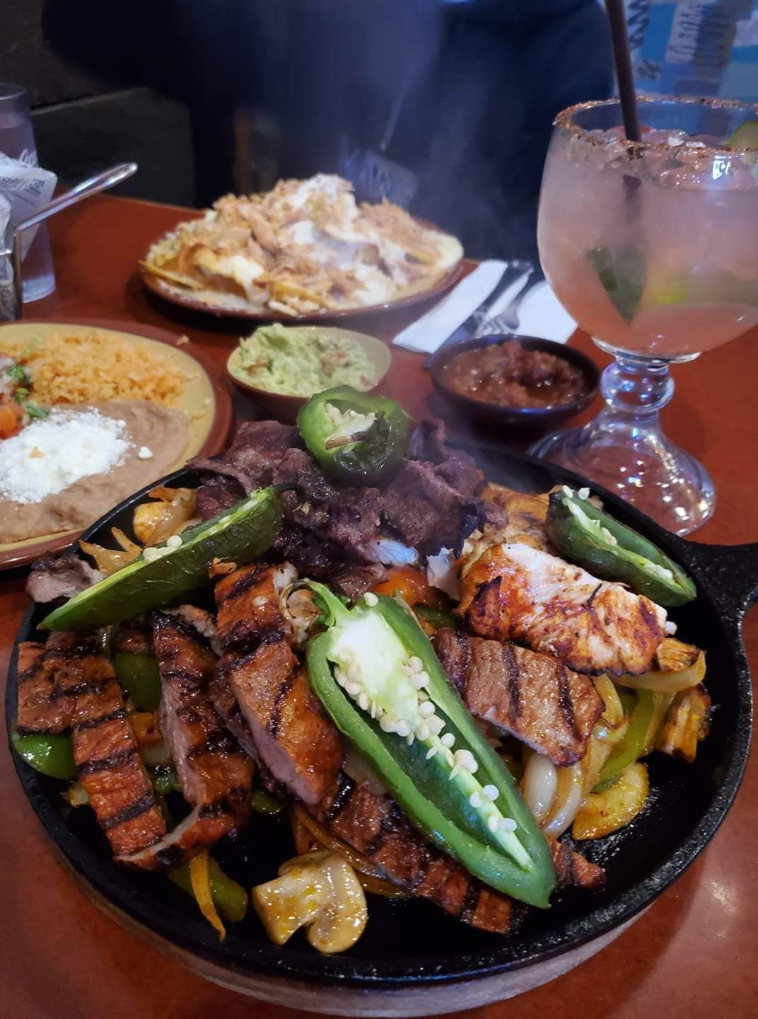 Sizzling fajitas with grilled meats, peppers and margarita